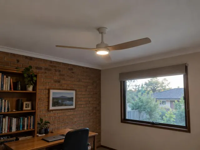 Living room with a ceiling fan on a plaster ceiling above a brick feature wall and window in Ashtonfield